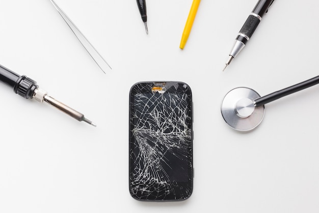 Photo top view broken smartphone with repair tools