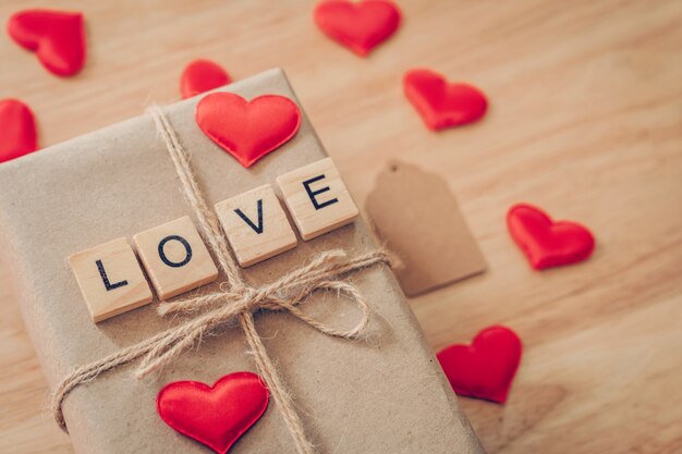 Top view brown gift box and red heart on wood background for valentine day with copy space.