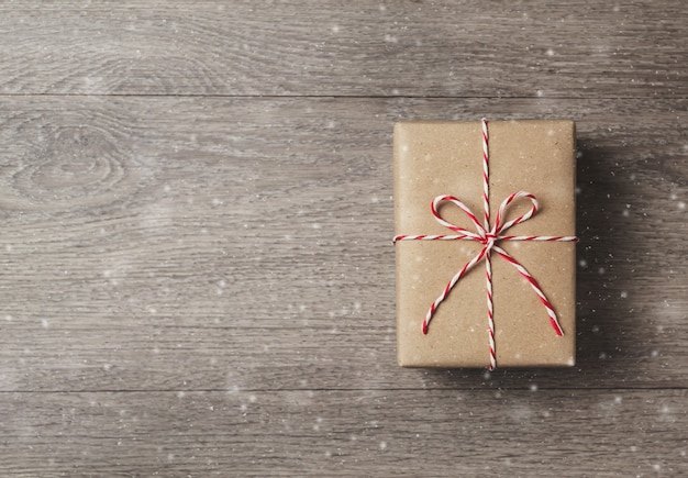 Foto vista superiore del contenitore di regalo marrone con la corda rossa su di legno.