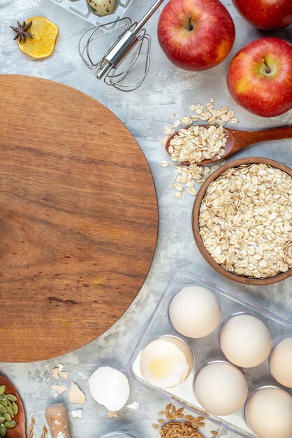 top view brown wooden desk with apples bananas eggs raw cereals and seeds on white background dough pie seed milk color corn cook cake