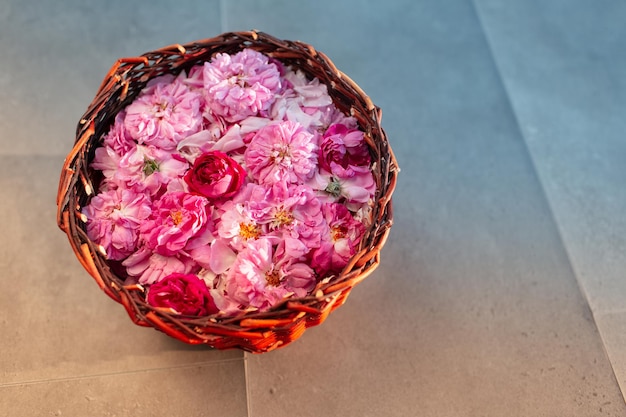 Вид сверху на букет чайных роз в деревянной корзине на фоне серого ламината