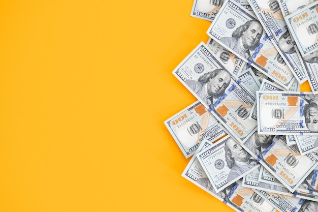 Photo top view of bundle of 100 dollar bill on yellow background business concept with copy space