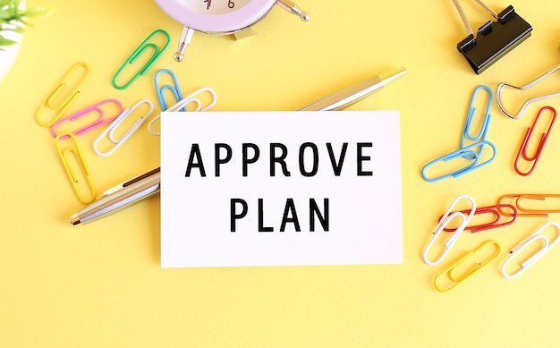 テキストAPPROVEPLAN、ペン、ペーパークリップ、時計付きの名刺の上面図