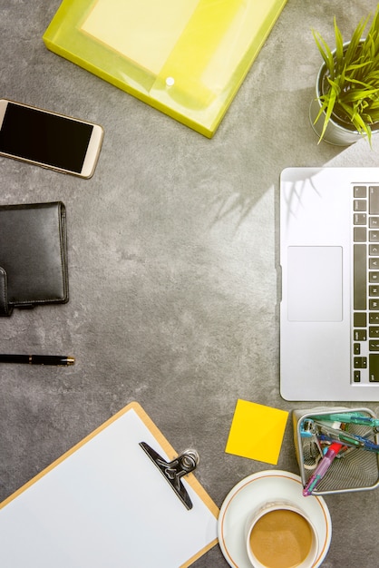 Top view of business desk with laptop, coffee, potted plant, document file, mobile phone and business accessories