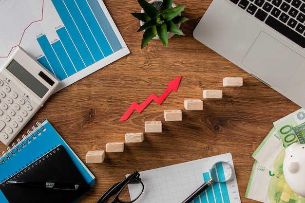 Top view of business items and growth arrow with wooden blocks