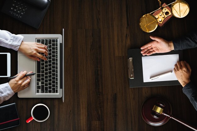 Photo top view business and lawyers discussing contract papers with brass scale on desk in office law legal services advice justice and law concept