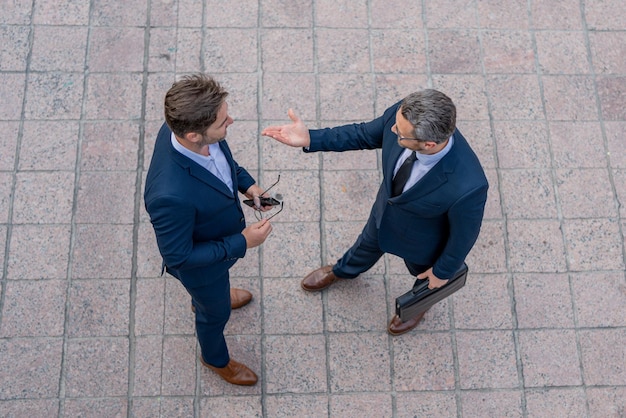 Foto vista dall'alto dell'uomo d'affari che parla durante una riunione all'aperto che elabora grandi piani con il capo business partner