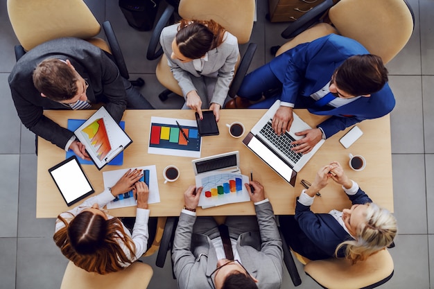 Top view of business people sitting at boardroom and working on important project for big client.