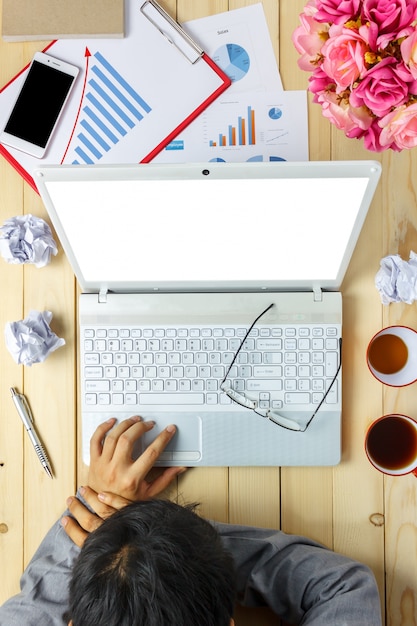 Top view business person sleeping on charts and graphs during discussing  also laptop,notebook,black coffee,stationary,pen,mobile phone on office desk background.