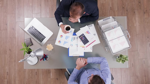 Top view of businessman in suit drinking coffee during collaboration meeting