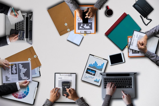 Top view businessmen team or financial data analysts working\
with tablets and laptop computers and data graphs together plan to\
analyzing projects in the office