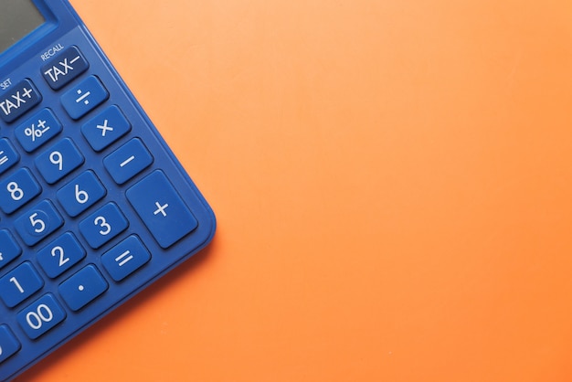 Top view of calculator on orange background with copy space