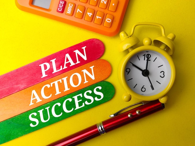 노란색 배경에 텍스트 PLAN ACTION SUCCESS가 있는 상위 뷰 계산기시계 및 펜