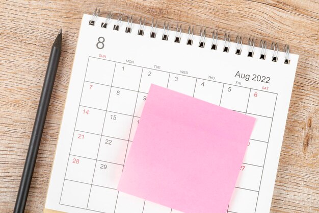 Top view calendar desk 2022 on August month, Calendar planning and pencil with sticky note on wooden background. Business planning appointment meeting concept