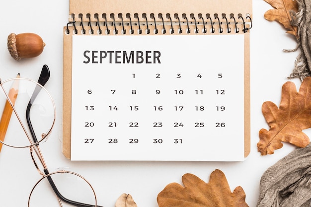 Top view of calendar with autumn leaves and glasses