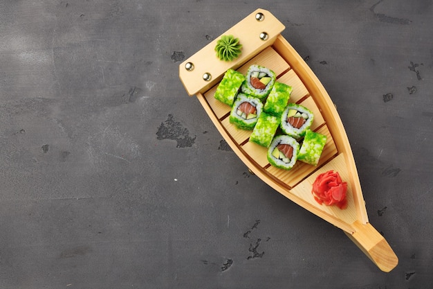 Top view of California sushi roll in plate on black background