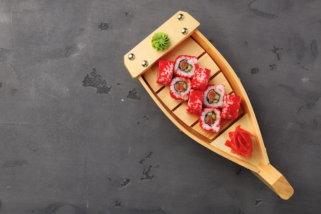 Top view of California sushi roll in plate on black table