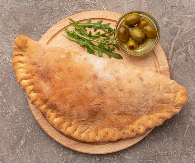 Foto vista dall'alto calzone, erbe aromatiche e olive