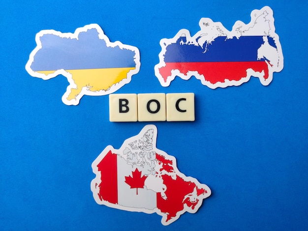 Photo top view canadarussia and ukraine flag with text boc on blue background