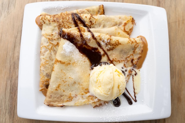 Vista dall'alto del piatto di crepes al latte condensato caramellato con gelato alla vaniglia e cioccolato