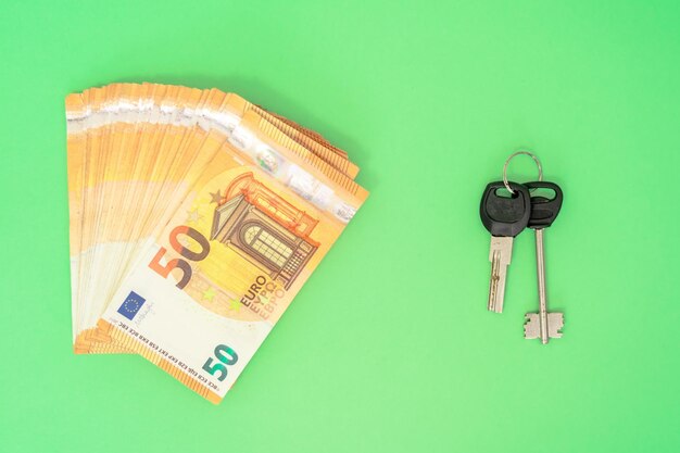 Top view of cash and keys on green background Real estate concept