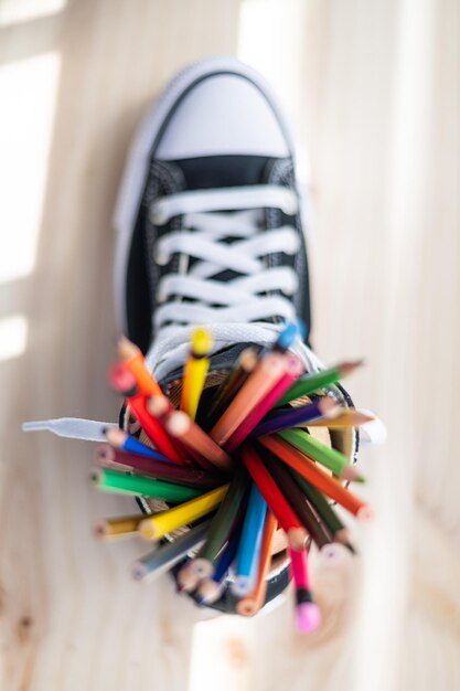 学校のコンセプトに戻る色鉛筆のセットを持つカジュアル スニーカーの平面図が背景をぼかし