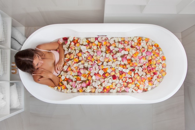 Top view of caucasian female in swimsuit sitting in bathtub with