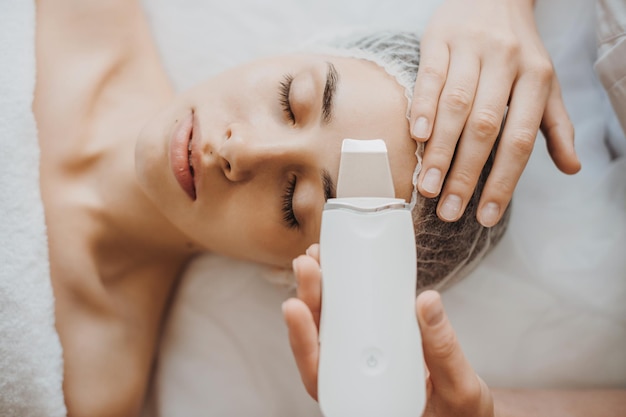 Top view of a caucasian woman getting skin analized by cosmetologists hands using skin analyzeredica