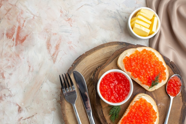 top view caviar sandwiches with cutlery on cutting board light surface