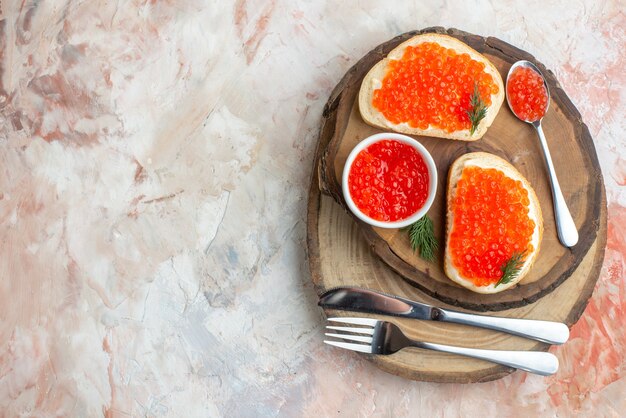 top view caviar sandwiches with cutlery on cutting board on light surface