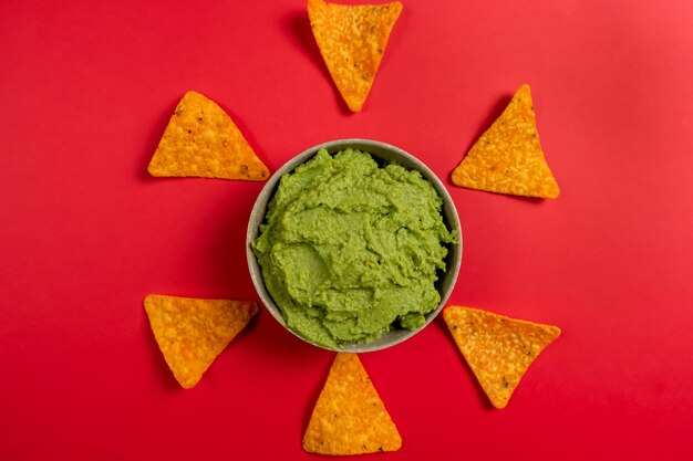 Top view of a ceramic bowl filled with the succulent guacamole sauce of mexican origin on a red background