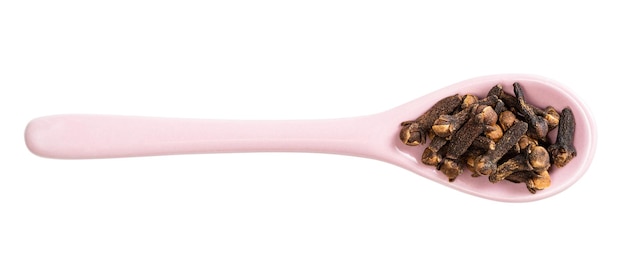 Top view of ceramic spoon with cloves isolated