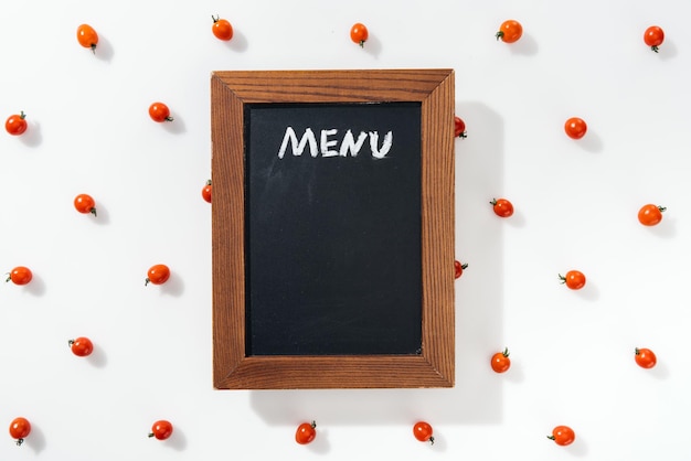 Photo top view of chalk board with menu lettering among cherry tomatoes
