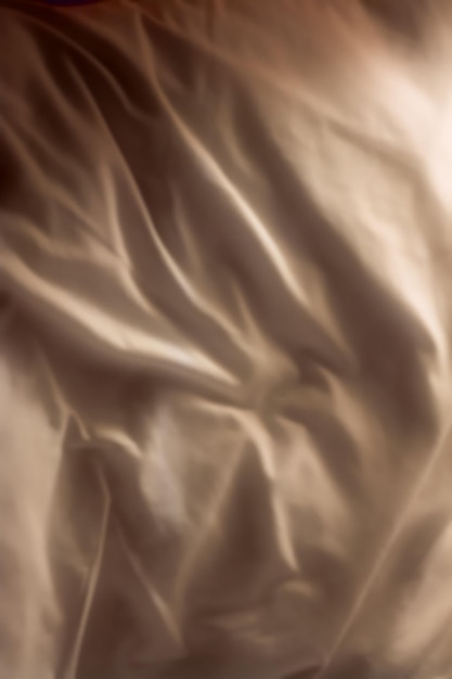 Top view of champagne coloured fabric background wrinkled natural linen material Closeup texture of a smooth satin or velvet sheets and luxurious cloth Abstract dark silk patterns or creases
