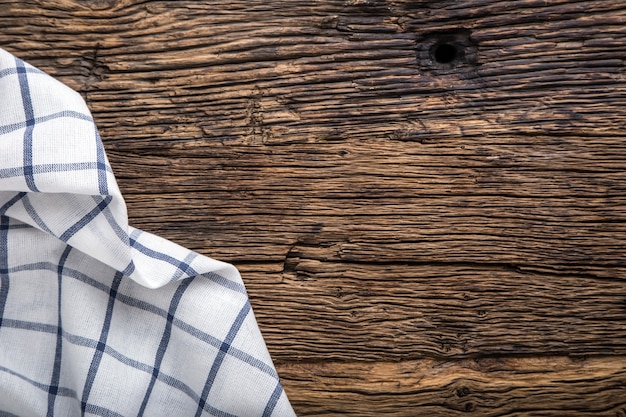 Top view of checkered tablecloth or napkin on empty wooden table.