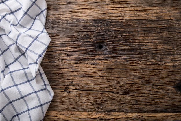 Top view of checkered tablecloth or napkin on empty wooden table.