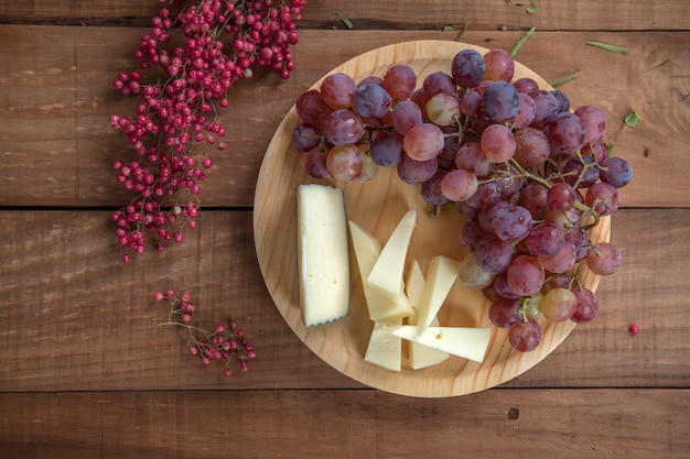 Top view of cheese plate with grapes on wooden table