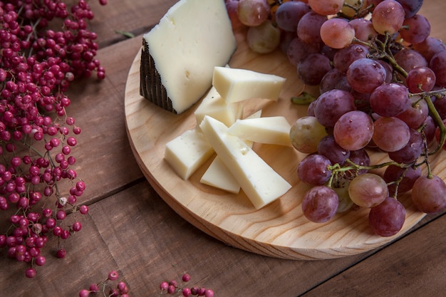 Top view of cheese plate with grapes on wooden table