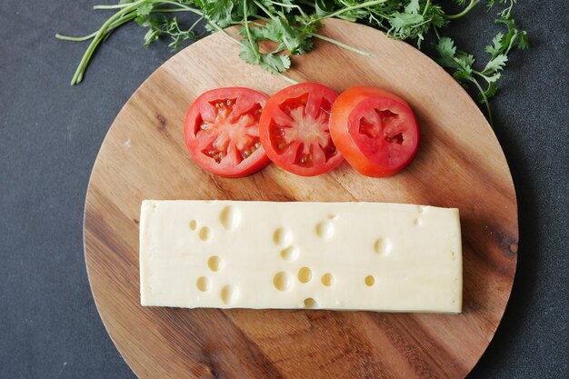 Top view of cheese and tomato on a chopping board on table