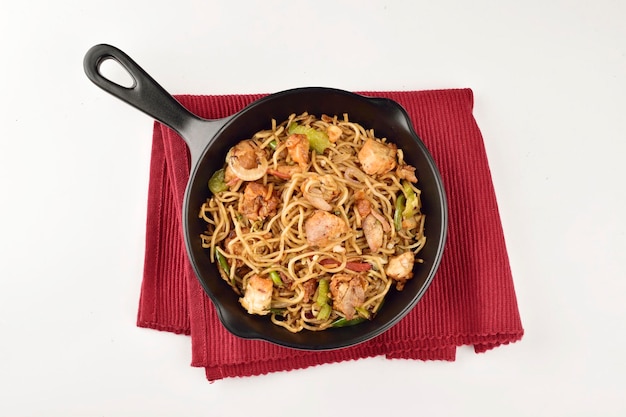 top view of chicken chow mein served in pan on white background