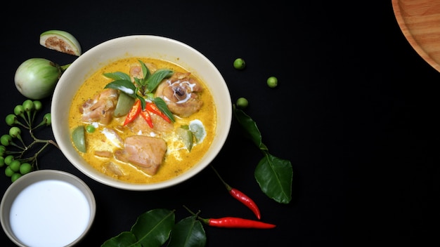 Top view of chicken green curry and ingredients on black desk background, Thai cuisine concept