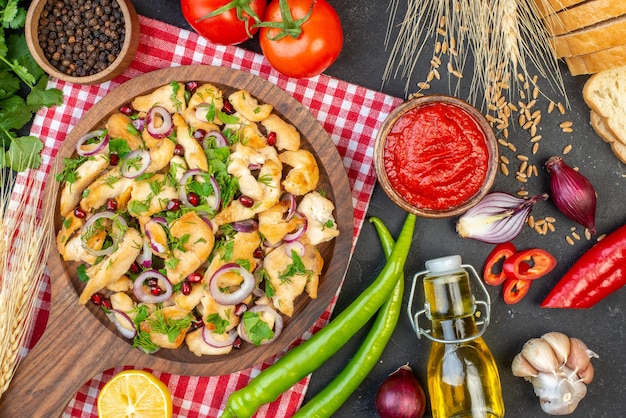 Top view chicken salad with vegetables and seasonings on dark surface