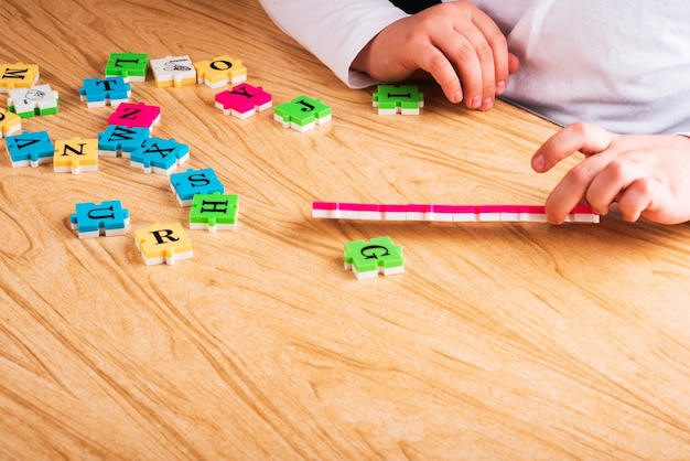 Top view of Child arm learning alphabet with puzzlein the table Copy space Learning in the form of a game concept