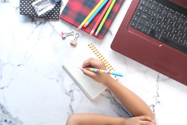 Photo top view of child girl hand writing on notepad