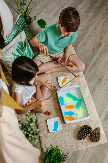 Photo top view of children playing fishing game at home