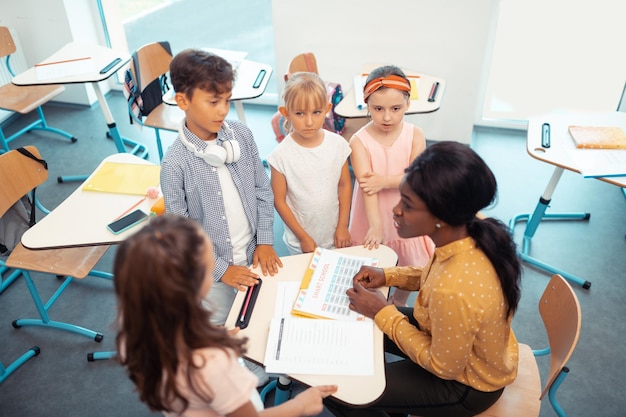 Top view of children standing around their teacher after lesson