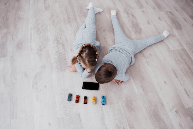 Top view. Children using digital gadgets at home. Brother and sister on pajamas watch cartoons and play games on their technology tablet