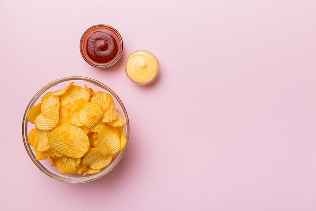 Photo top view chips with sause in bowl on colored background top view with copy space