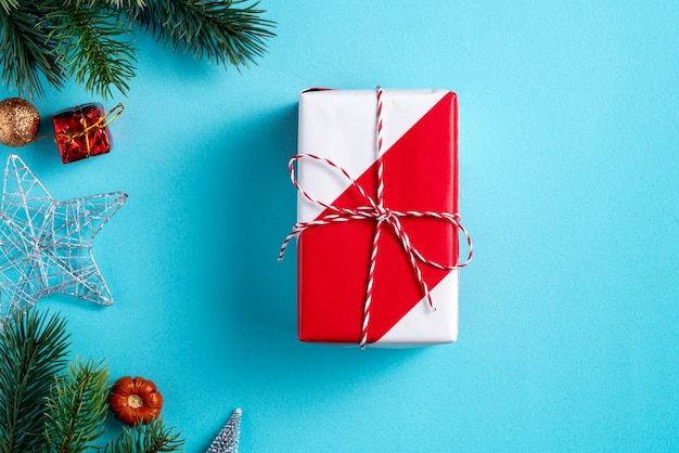 Top view of Christmas background design concept with gift box and fir tree branch decoration on blue table background.