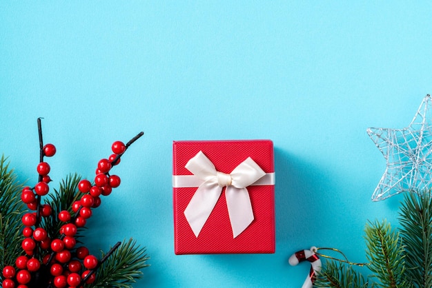 Top view of Christmas background design concept with gift box and fir tree branch decoration on blue table background.